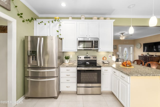 kitchen with light stone countertops, appliances with stainless steel finishes, hanging light fixtures, white cabinets, and kitchen peninsula