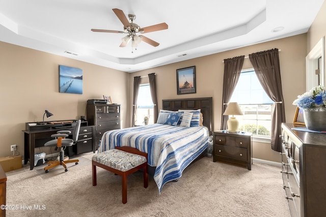 bedroom featuring ceiling fan, light carpet, and a tray ceiling