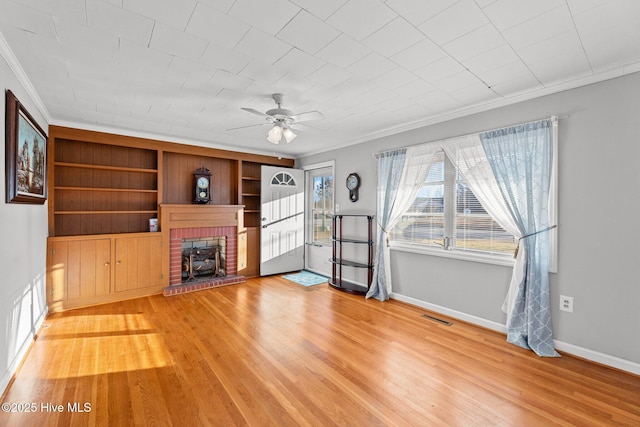 unfurnished living room featuring hardwood / wood-style flooring, ceiling fan, ornamental molding, and a fireplace