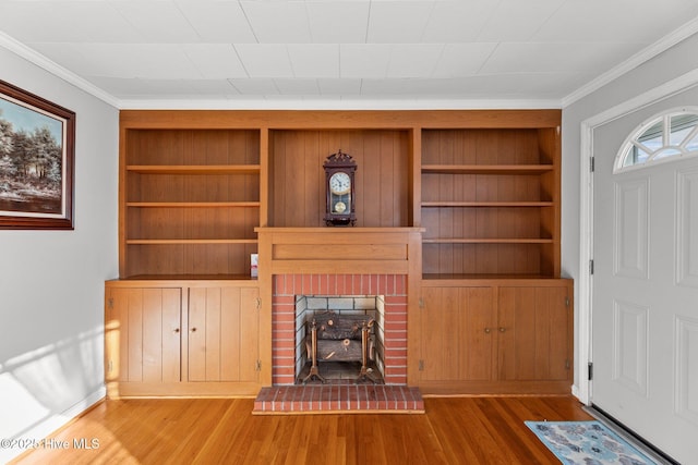 unfurnished living room featuring wood-type flooring, ornamental molding, and built in shelves