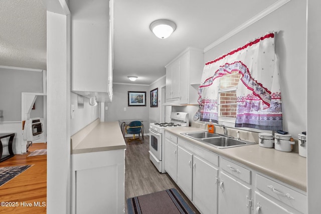 kitchen featuring ornamental molding, gas range gas stove, heating unit, sink, and white cabinetry