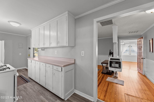 kitchen featuring white cabinets, light wood-type flooring, white appliances, and heating unit