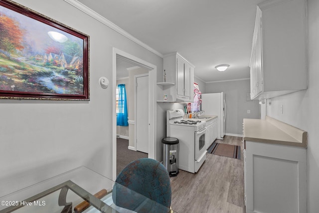 kitchen with white appliances, white cabinets, sink, ornamental molding, and light hardwood / wood-style floors