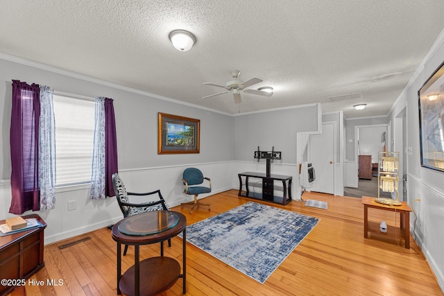 sitting room with wood-type flooring, a textured ceiling, and crown molding