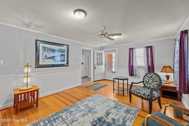 living area with crown molding, a textured ceiling, and hardwood / wood-style flooring