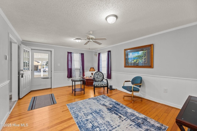 sitting room with hardwood / wood-style flooring, ceiling fan, ornamental molding, and a textured ceiling