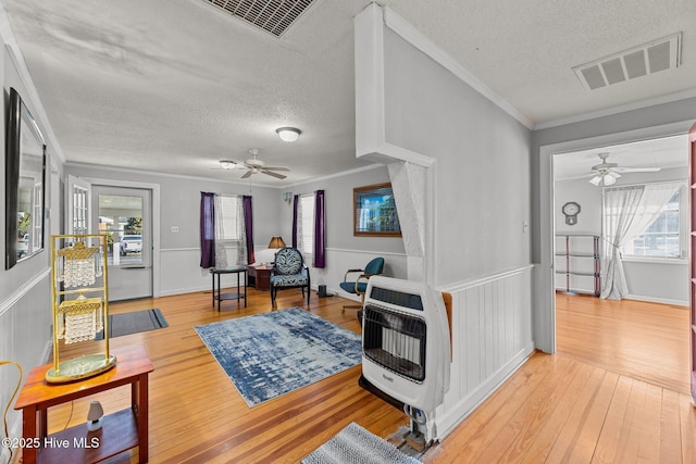 living room with heating unit, hardwood / wood-style floors, a textured ceiling, and ornamental molding