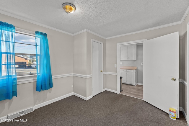 empty room with dark colored carpet, crown molding, and a textured ceiling