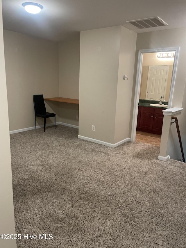 carpeted empty room with built in desk and sink