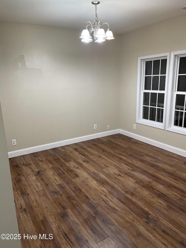 unfurnished room featuring dark hardwood / wood-style flooring and an inviting chandelier