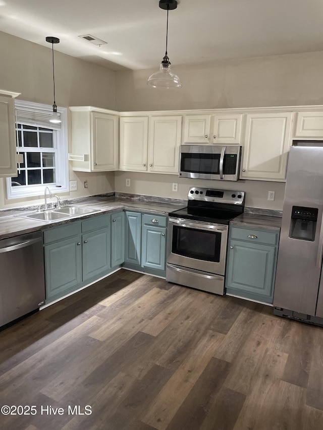 kitchen featuring white cabinets, appliances with stainless steel finishes, pendant lighting, and sink