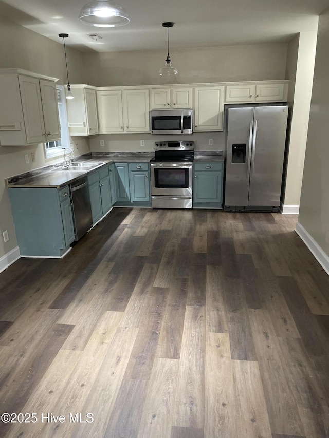 kitchen with decorative light fixtures, sink, stainless steel appliances, and dark wood-type flooring