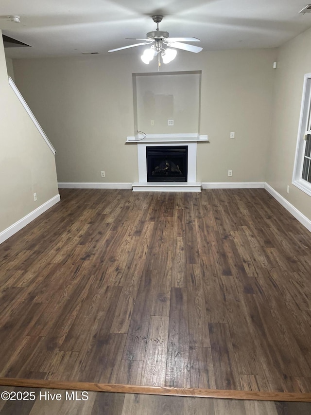 unfurnished living room featuring ceiling fan and dark wood-type flooring