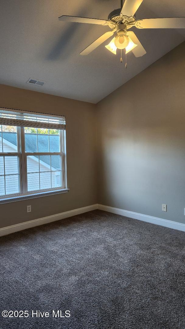 carpeted spare room featuring ceiling fan and vaulted ceiling