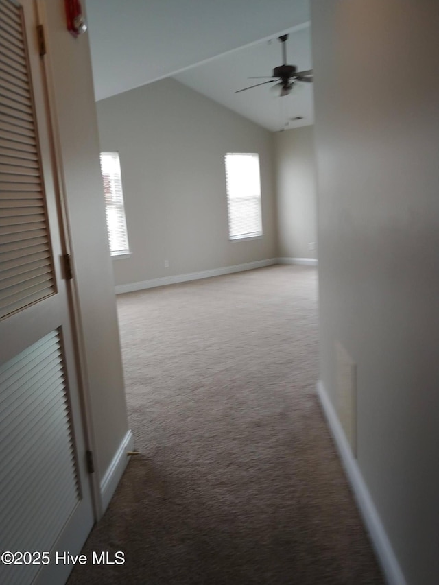 hallway featuring plenty of natural light, light colored carpet, and vaulted ceiling