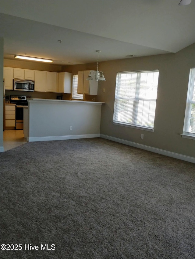 kitchen featuring kitchen peninsula, carpet flooring, stainless steel appliances, decorative light fixtures, and white cabinetry