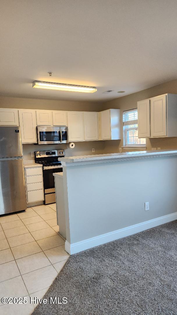 kitchen with white cabinetry, light tile patterned flooring, and stainless steel appliances