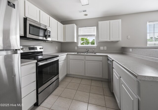 1422 Willoughby Park Ct Unit 5, Wilmington, NC 28412 - kitchen with appliances with stainless steel finishes, a sink, a peninsula, white cabinetry, and light tile patterned floors