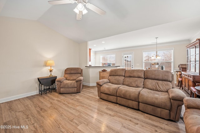 living room with vaulted ceiling, crown molding, light hardwood / wood-style floors, and ceiling fan with notable chandelier