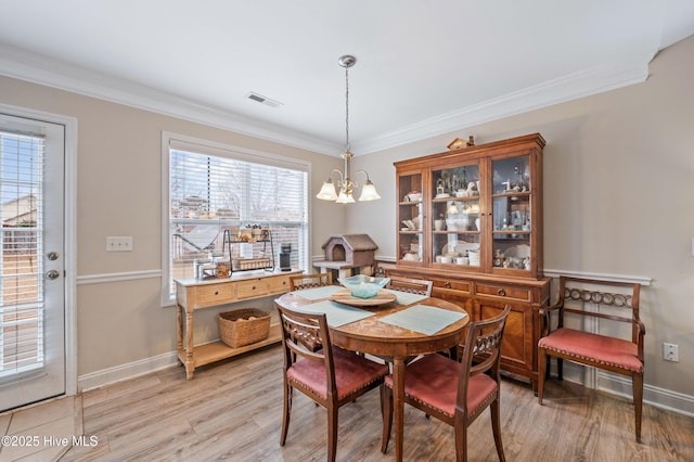 dining area with light hardwood / wood-style flooring, ornamental molding, and a notable chandelier