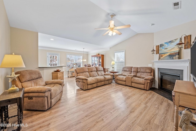 living room with ceiling fan, light hardwood / wood-style floors, and vaulted ceiling