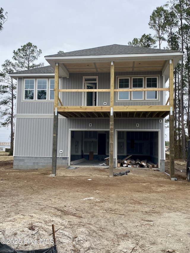 rear view of house featuring board and batten siding, roof with shingles, and a balcony