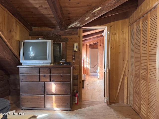 interior space with light hardwood / wood-style floors, wooden ceiling, wood walls, and lofted ceiling with beams