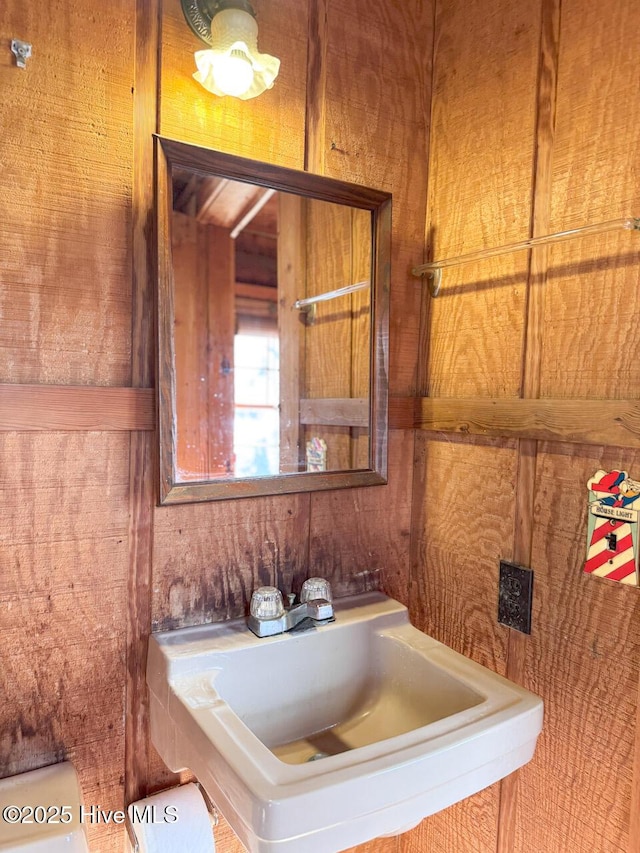 bathroom featuring sink and wooden walls