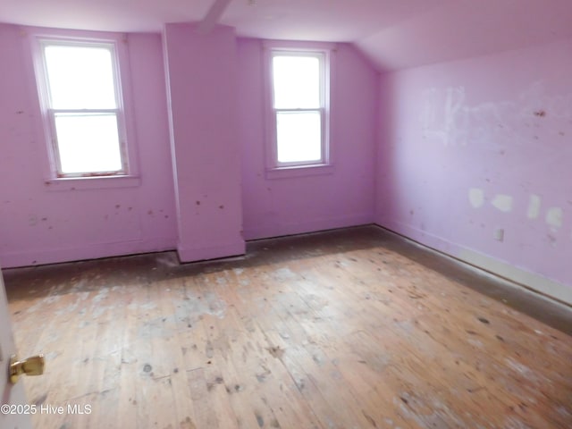 additional living space with light hardwood / wood-style flooring and lofted ceiling