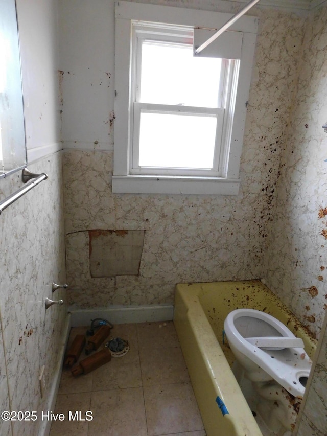 bathroom with toilet, tile patterned floors, and a bathing tub