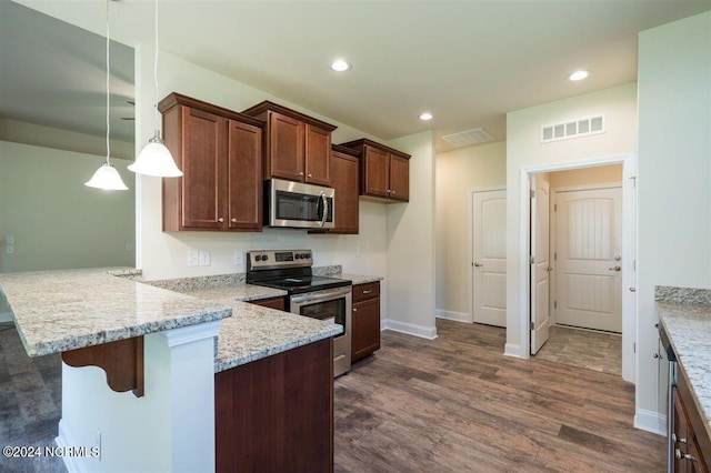 kitchen with dark wood-type flooring, a breakfast bar area, decorative light fixtures, kitchen peninsula, and stainless steel appliances