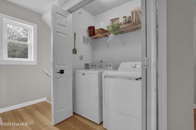 washroom featuring a textured ceiling, light wood-type flooring, and separate washer and dryer