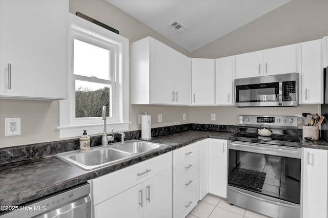 kitchen with lofted ceiling, white cabinetry, and appliances with stainless steel finishes