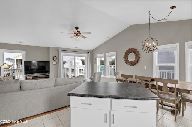 kitchen featuring pendant lighting, a kitchen island, white cabinetry, ceiling fan with notable chandelier, and light tile patterned flooring