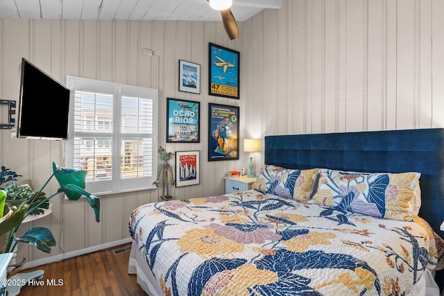 bedroom featuring ceiling fan, wood walls, and dark wood-type flooring