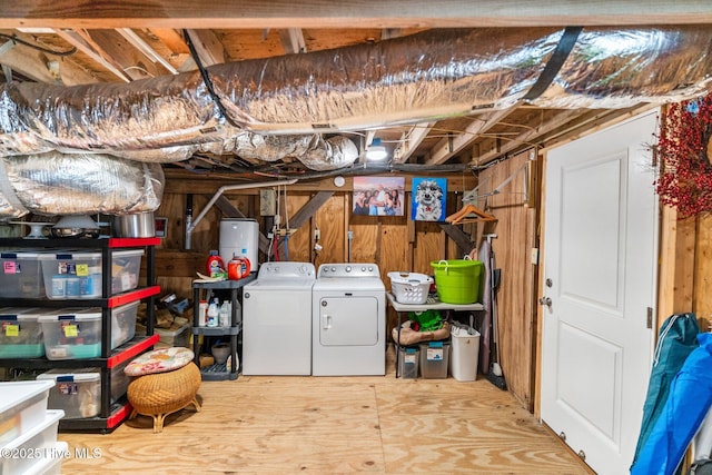 basement with washing machine and dryer, electric water heater, and wood walls