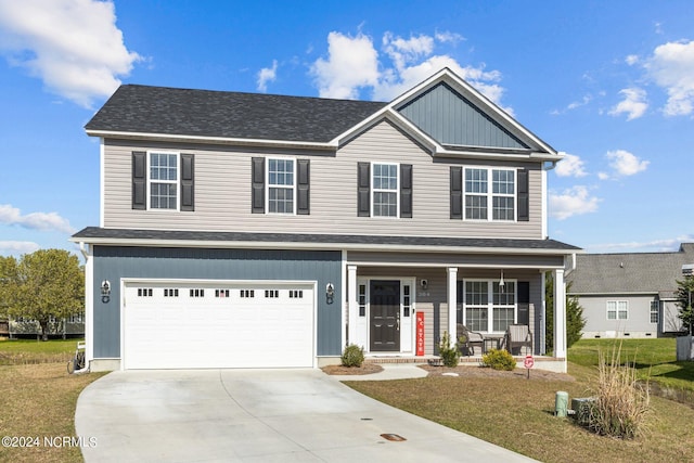 view of front of property with covered porch, a garage, and a front yard