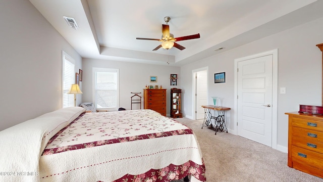 carpeted bedroom featuring a raised ceiling and ceiling fan