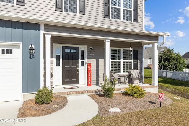 view of exterior entry with a porch and a garage