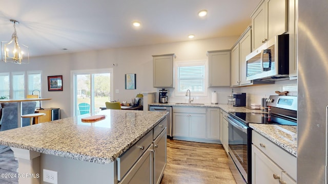 kitchen featuring pendant lighting, plenty of natural light, a center island, a notable chandelier, and stainless steel appliances