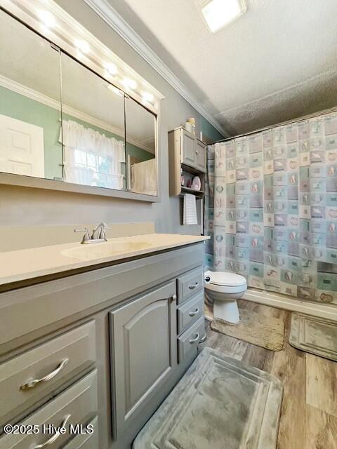 bathroom featuring wood-type flooring, vanity, toilet, and crown molding