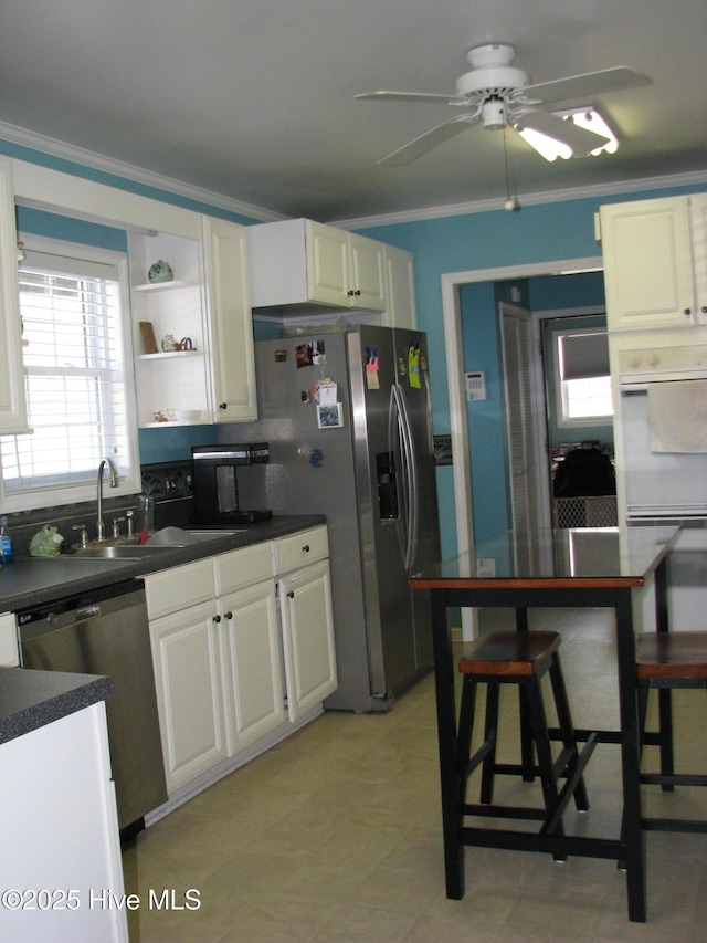 kitchen featuring appliances with stainless steel finishes, ceiling fan, crown molding, sink, and white cabinets