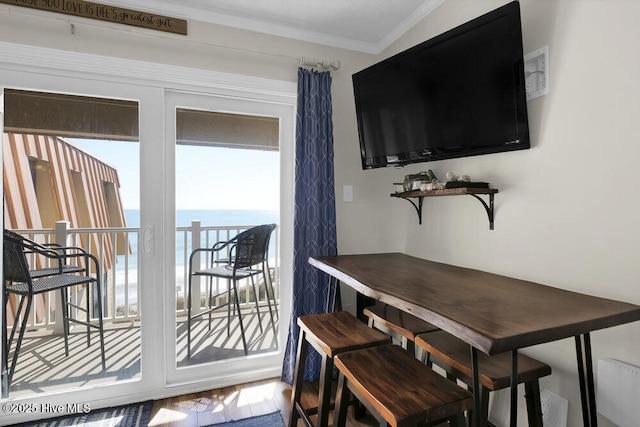 dining area with hardwood / wood-style flooring, a water view, and ornamental molding