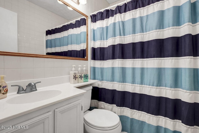 bathroom with curtained shower, vanity, and toilet