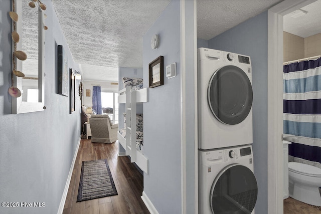 washroom with dark hardwood / wood-style floors, a textured ceiling, and stacked washer and clothes dryer