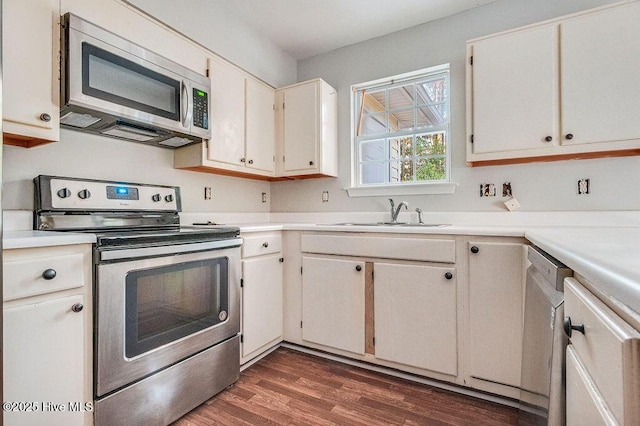 kitchen featuring appliances with stainless steel finishes, white cabinetry, dark wood-type flooring, and sink