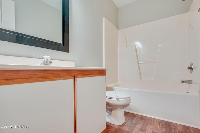 bathroom with hardwood / wood-style flooring, toilet, and shower / washtub combination