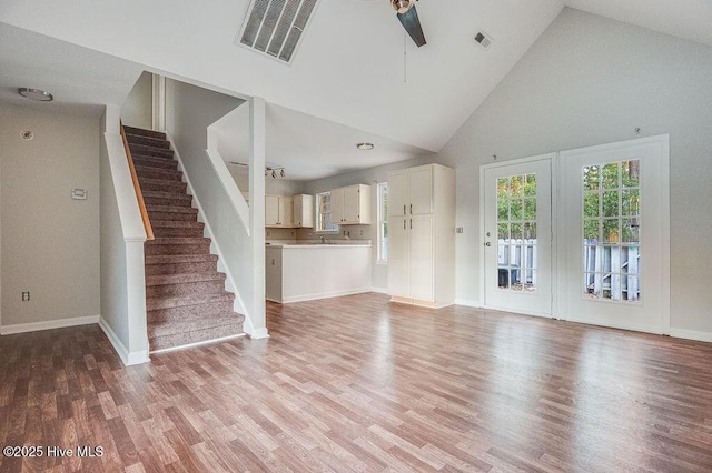 unfurnished living room with light hardwood / wood-style floors, high vaulted ceiling, and ceiling fan