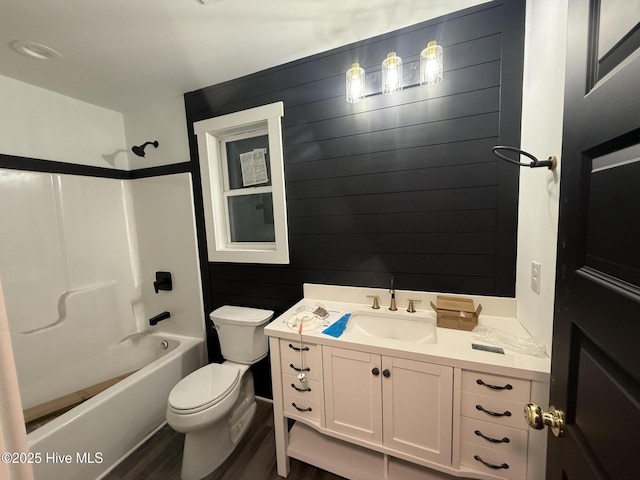 full bathroom featuring toilet, wood walls, vanity, hardwood / wood-style flooring, and shower / bath combination