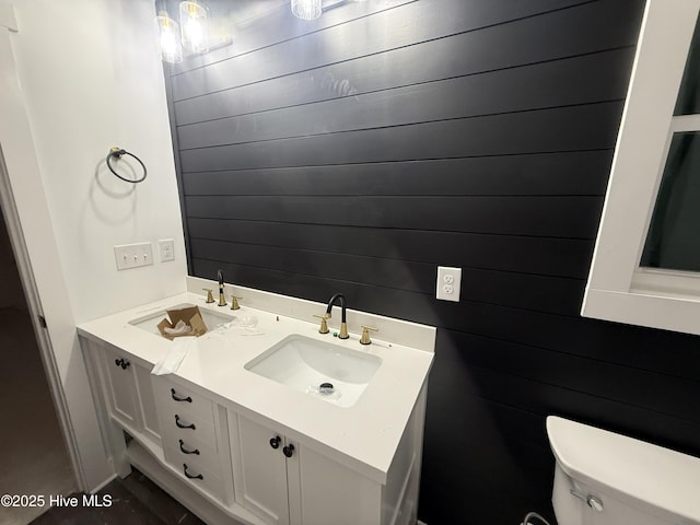 bathroom with vanity, wooden walls, and toilet